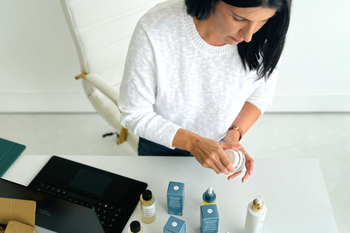 Woman packing summer beauty essentials in suitcase