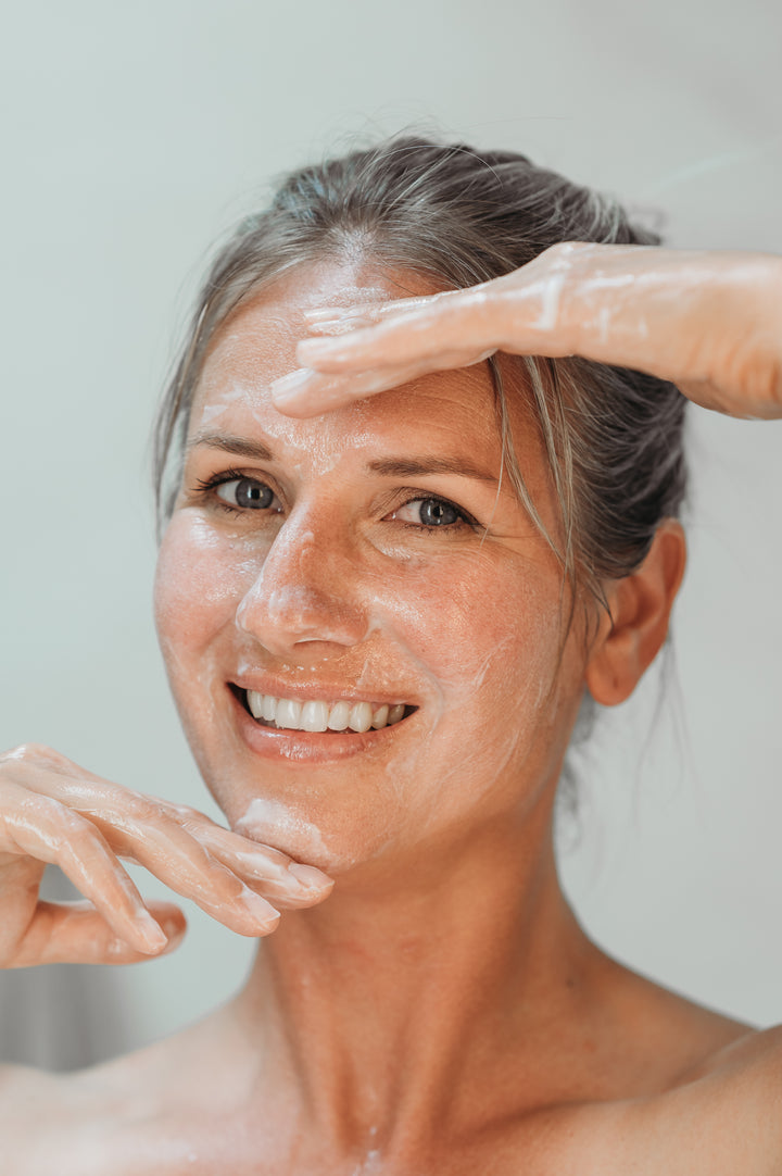 Model massaging Aurora Cleanser into face by EMK Skincare