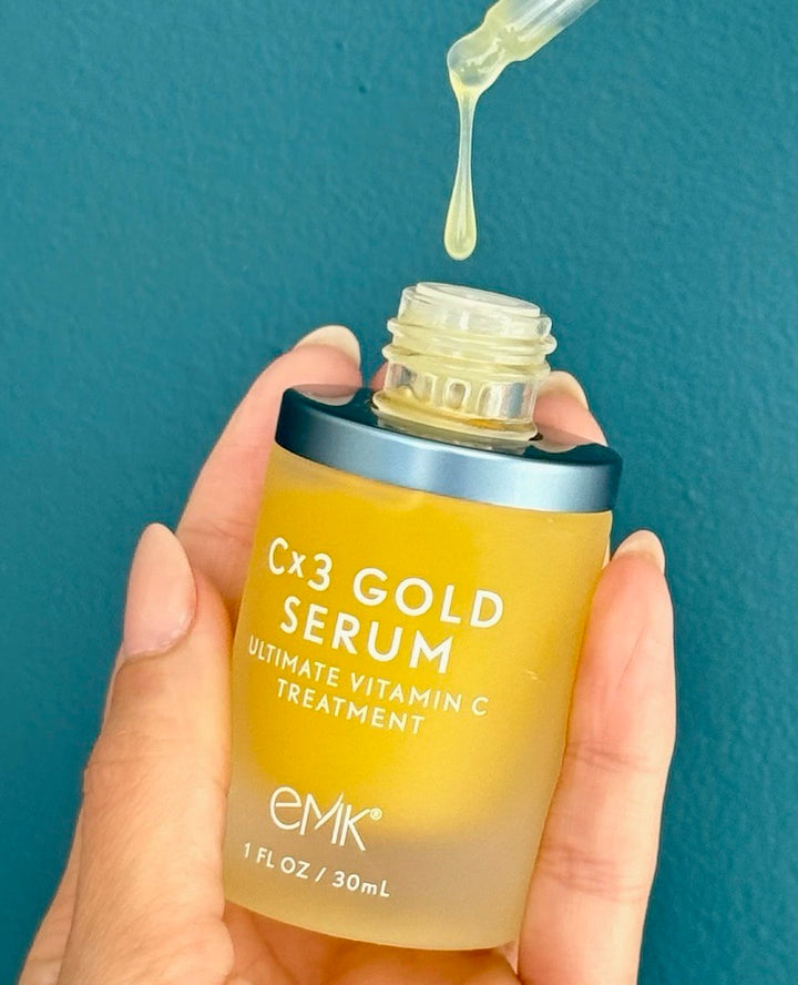 Cx3 Gold Serum bottle held with dropper dripping by EMK Skincare