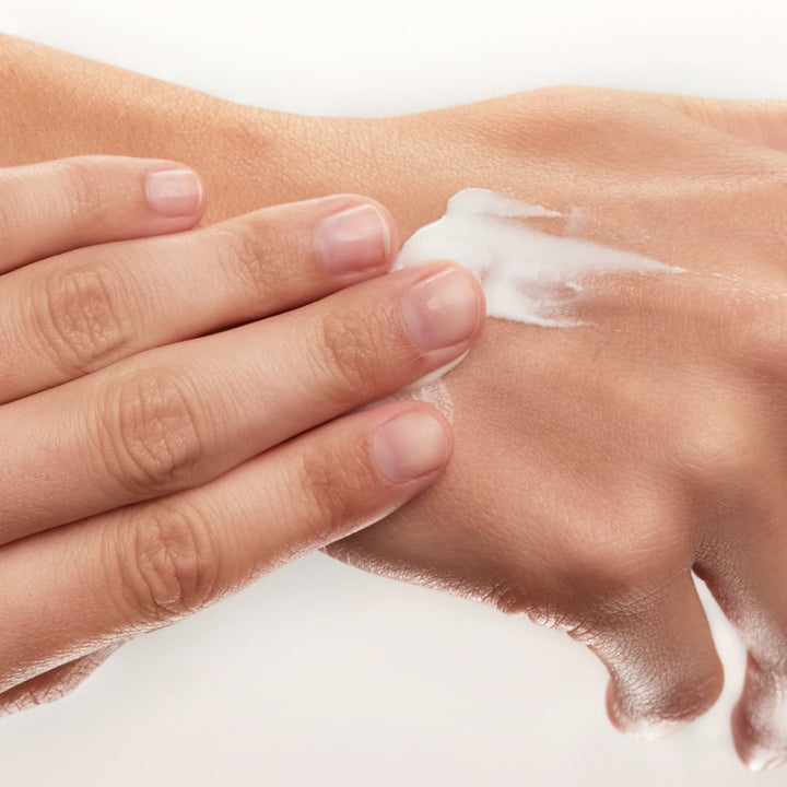 Model applying Lumina Hand Treatment to the back of the hand by EMK Skincare
