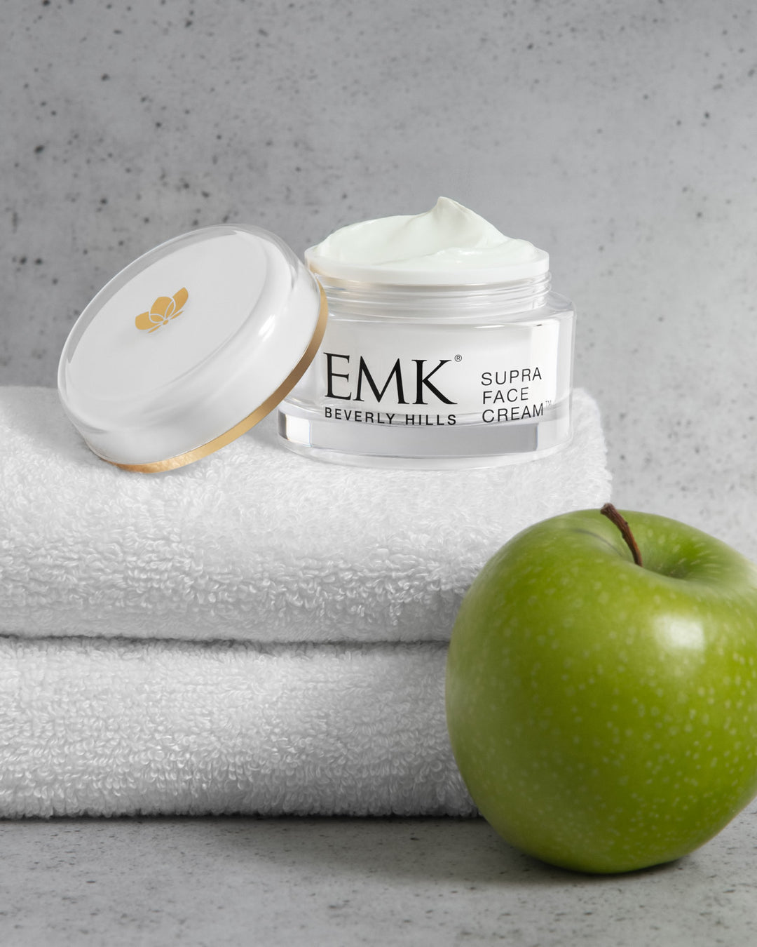Supra Face Cream open jar styled with white towels and a green apple, EMK Skincare